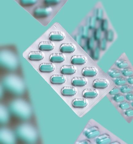 A whimsical arrangement of floating pill blister packs against a teal backdrop, highlighting healthcare themes.